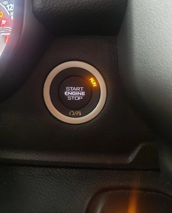 Start/stopp-brytare i en bil med texten "START ENGINE STOP" och en lampa som lyser "RUN".