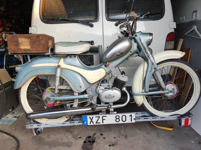 Helikama Hopeasiipi moped från 1960 i patinerat skick, utrustad med en 3-växlad Sachs motor och en trälåda bak, står i ett garage.
