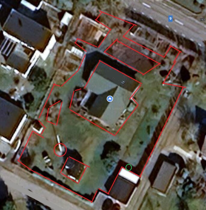 Flygfoto av en tomt med ett stort hus i centrum, omgivande byggnader och markerade gränser i rött.