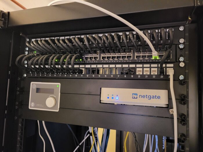 Monterad serverrack med inkopplade nätverkskablar och en Netgate-enhet, fotograferad innan aktuella diskussionstråden.