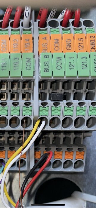 Elektrisk kopplingspunkt med flera kablar anslutna; inkluderar orange och gröna terminalklämmor.