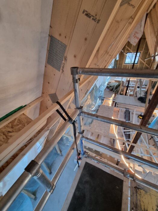 Byggställning med plattformar och stag i träbyggnad, sedd uppifrån.