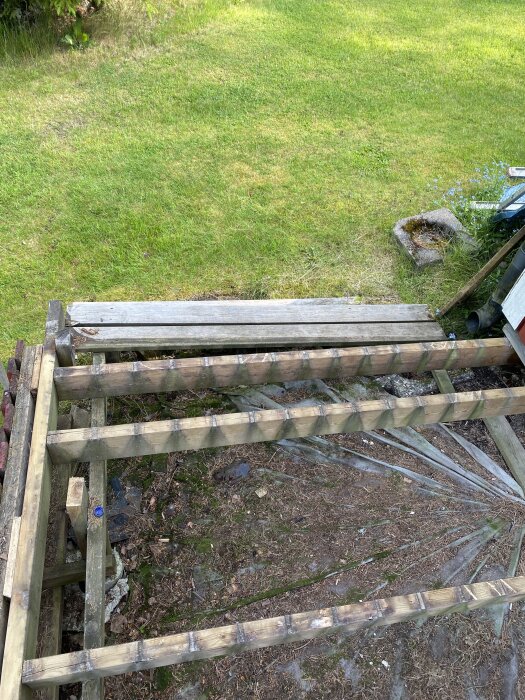 Träunderrede till en altantrappa under renovering med mark som lutar i sidled och ett vangstycke som behöver stärkas.