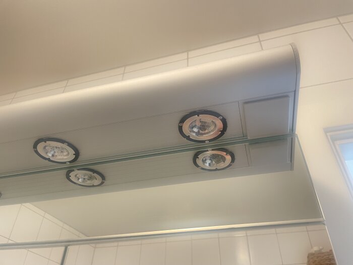 Spotlights installerade i en badrumsskåpsram utan skydd.