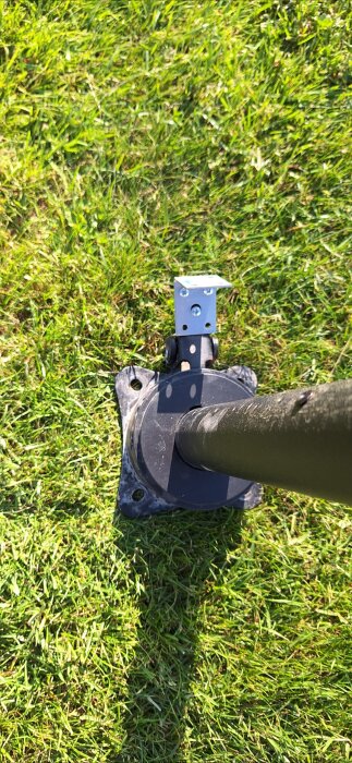 Basen av ett parasoll med fotpedal, stående på gräs, som ska gjutas in i en plint för ökad stabilitet.