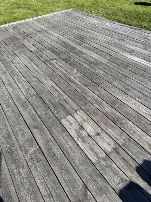 Gammal träaltan med grått och smutsigt utseende, delvis rengjord plats där den ursprungliga färgen syns igen. Gräsmatta i bakgrunden.