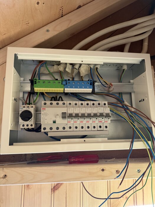 Inuti en Hager Delta infälld normcentral med inkopplade DIN-skenor, brytare och JFB; synliga anslutningskablar och verktyg.