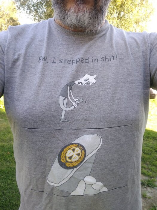 En t-shirt med en tecknad figur som säger "Ew, I stepped in shit!" och visar en sko med en logga på sulan.