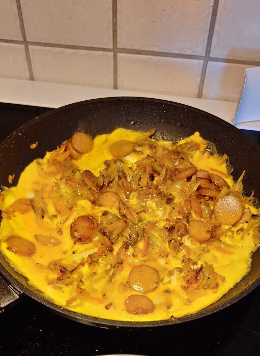 Stekt omelett-lik maträtt med riven potatis, morot, lök och ägg i gjutjärnspanna, kryddad med salt, peppar, och paprikapulver.