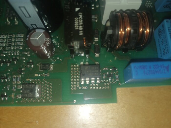 Kretskort med lödkontakter och komponenter, inklusive kondensatorer och en spoltråd, påträffade i ett elektriskt reparationsprojekt.