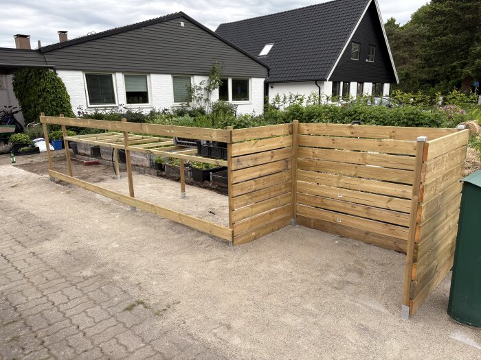 Bygget av ett planteringsbord utomhus med träram och plankstaket i tryckimpregnerat virke, utan plåtar eller skydd på bordets yta.