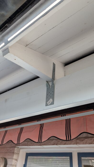 Byggkonstruktion med vit bärlina fäst i tak med metallkonsol ovanför altandörr; sökande efter stabil och hållbar avlastning.