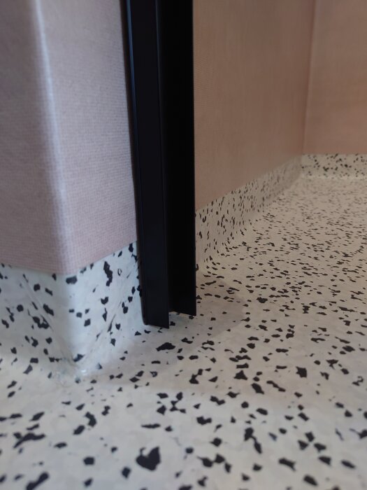 Aluminiumlist monterad i duschhörn med korkmatta och mjuk böj i golvet.