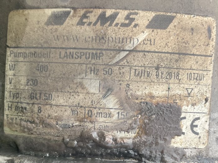 Etikett på smutsig dräneringspump från företaget E.M.S. med specifikationer: pumpmodell Länspump, 400 W, 230 V, GLI 5.0, maxhöjd 8 m, CE-märkt.