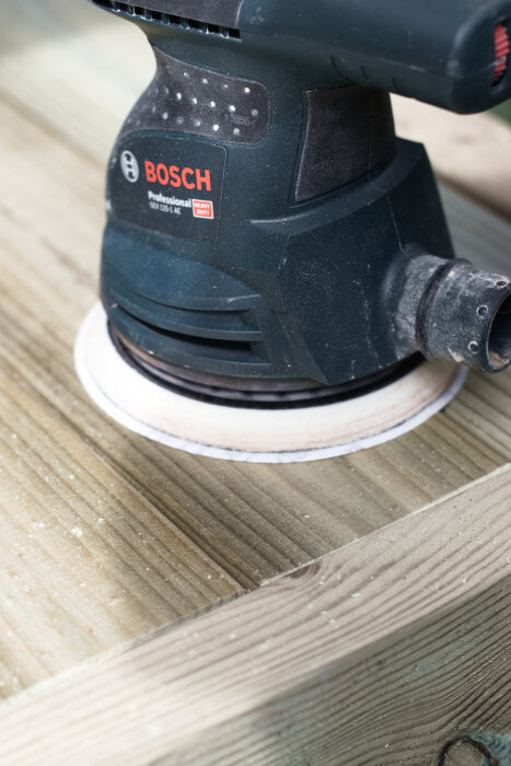 En Bosch excenterslip som används för att slipa en träram till ett hemmabyggt utekök eller omplanteringsbänk.