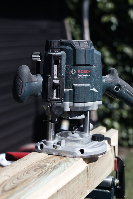 En Bosch Professional överhandsfräs används på en träbräda som en del av ett utomhusköks- eller omplanteringsbänksprojekt.