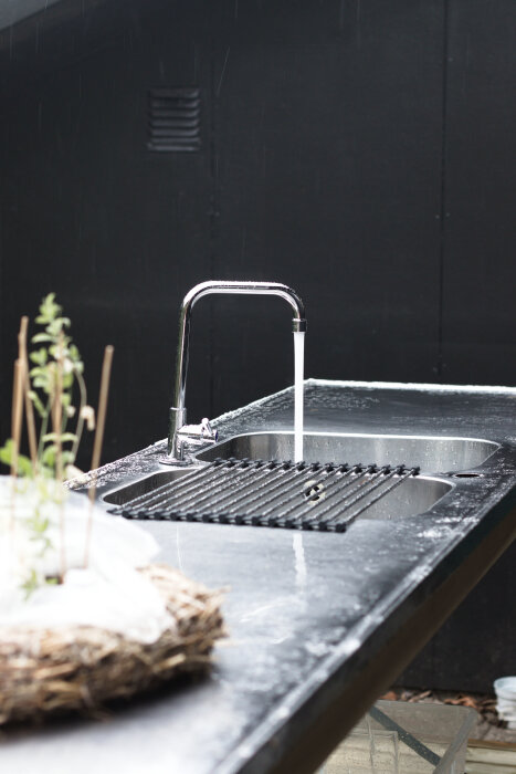 Utekök med rostfri diskho och rinnande vatten från kranen, designat för omplantering av växter.