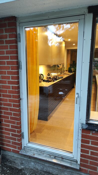 Glasdörr vid tegelvägg, öppnad inåt. Diskussion om att hänga om dörren så den öppnas utåt åt andra hållet.