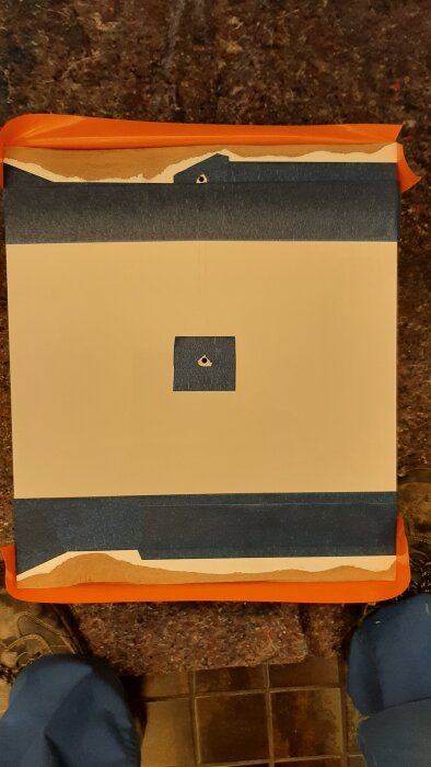 Dörr med orange och blå maskeringstejp, redo för fyllning och slipning, del av renoveringsprocess där kemiskt trä ersatt skadat MDF-material.