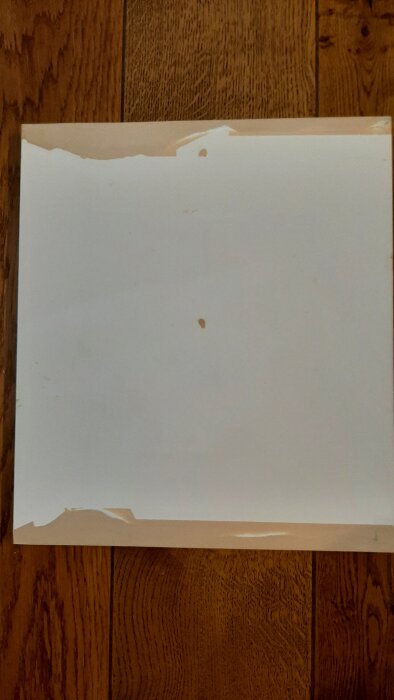 Dörr med bortskurna skadade kanter, fylld med kemiskt trä, på en mörkbrun trägolvbakgrund.