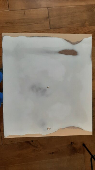 Reparerad MDF-dörr med fyllda och slipade ytor, omgiven av maskeringstejp och kemiskt trä för att laga skadat material.