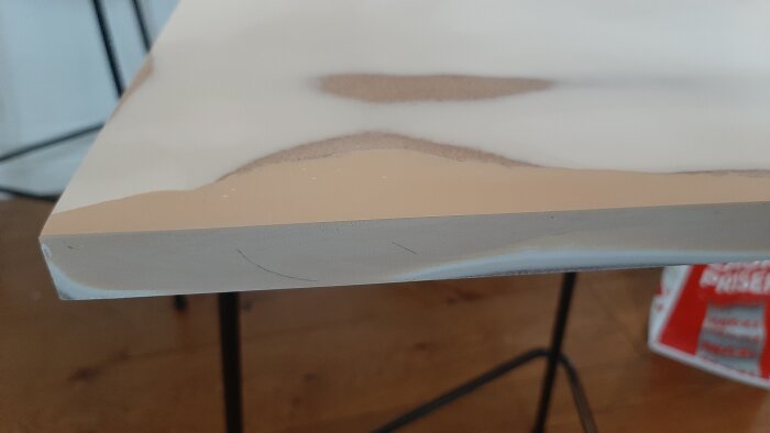 Närbild av en MDF-skiva med lagade håligheter och ojämnheter, slipad och förberedd för målning, del av renoveringsprojekt.