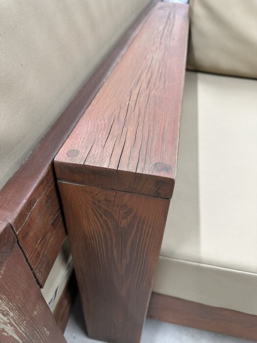 Utomhus loungeset i trä, närbild av armstöd med synlig träådring och eventuell betsning eller oljning; används för identifiering av träslag.