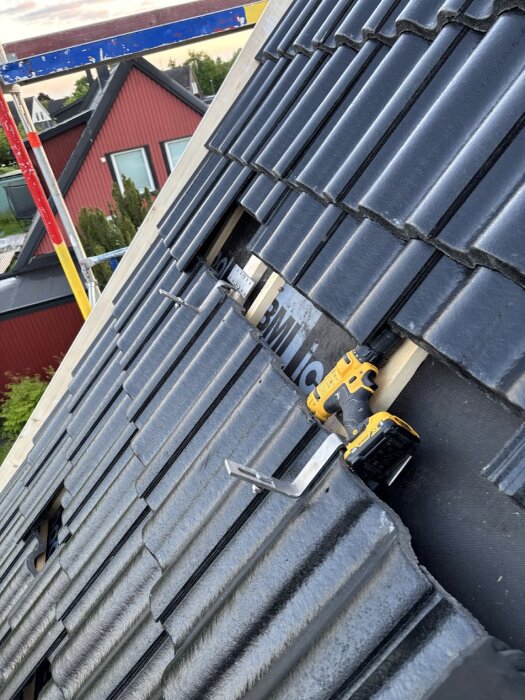 Tak med montering av solcellspanelsfästen, synlig plywood och skenor. Verktygshylla i förgrunden, närbild på ett brant takarbete.