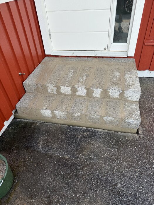 Trappavsats i lecasten nyss murad med cementbruk, placerad vid en röd yttervägg.