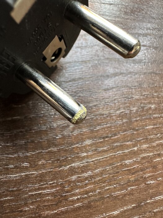 Metallkontakten på en elkontakt med gulnande och något "smält" utseende, vilket kan indikera överhettning.