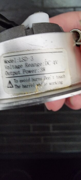 Närbild av en apparat med etikett som visar modellnummer "LSD 3" och spänningsområde "DC 4V".