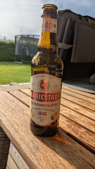 Flaska med Mariestads Alkoholfri öl på träbord utomhus.