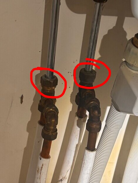 Rörkopplingar under ett handfat med två muttrar, omringade i rött, där en siffra 15 syns på ena muttern.