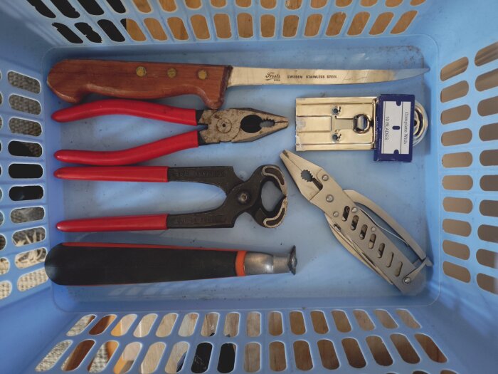 Korg med verktyg inklusive Knipex-tänger, mora filekniv, skruvmejsel och rakblad.