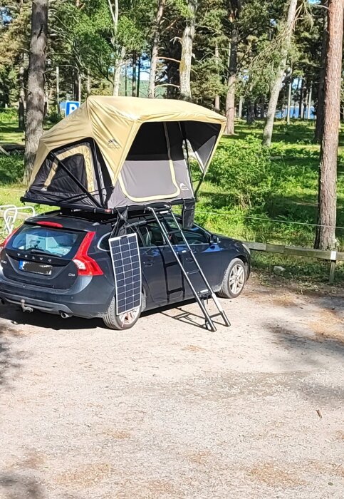 Bil med tält på taket i Brandalsund naturreservat, solpanel monterad vid sidan, omgiven av skog.