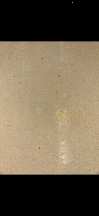 Ljusa, porösa spånskivor med slät yta och en synlig avskavd del som exponerar en gul ton under; potentiella limrester eller grundfärg.