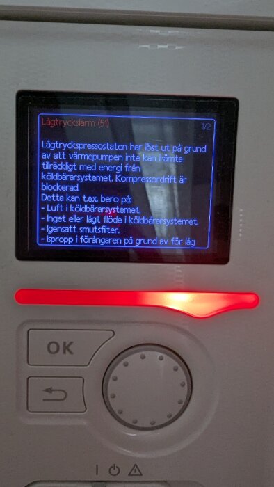 Värmepumpens display visar ett lågt trycklarm på grund av luft i köldbärarsystemet eller igensatt smutsfilter. Röd varningslampa lyser.