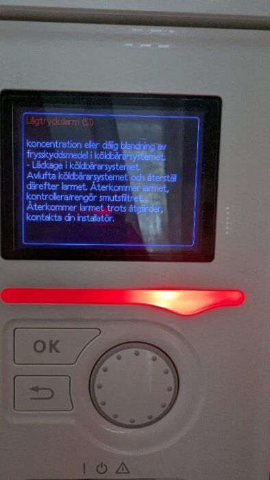Bild på en värmepumpsdisplay som visar ett lågtryckslarm och instruktioner om avluftning och rengöring av smutsfilter.
