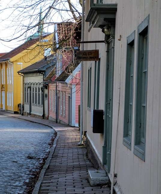 Charmig gata med färgglada trähus och trottoar; eventuell diskutabel hemfridszon visas mellan hus och trottoar.