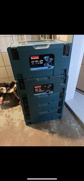 Staplade Makita-verktygslådor i ett garage på ett betonggolv.