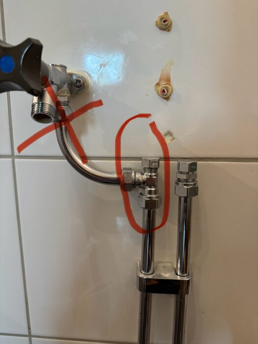 Vattenkoppling på kakelvägg, vänster sida konisk med täcklock och höger sida plan koppling med lekande mutter, i röd markering.