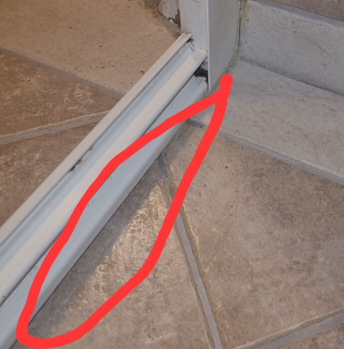 Duschgolvkant utan silikon vid glasvägg, markerat med röd linje. Golvet och väggen är täckta med ljusa keramiska plattor.