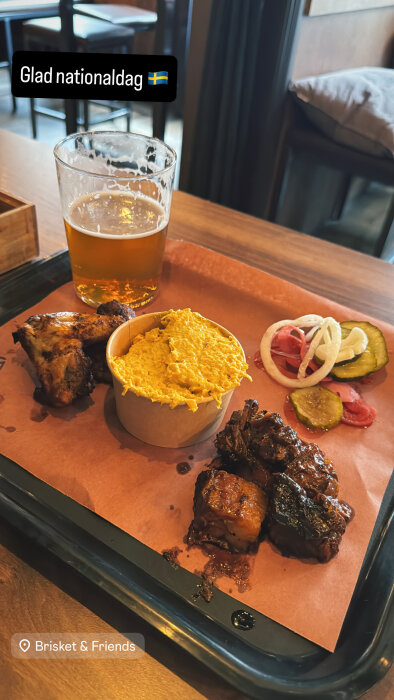 Fat med öl, kyckling, grillat kött, gul röra och picklade grönsaker på en träbord.