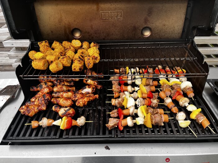 Grill med majskolvar, grillade kycklingbitar och grillspett med kött, svamp, paprika och lök.