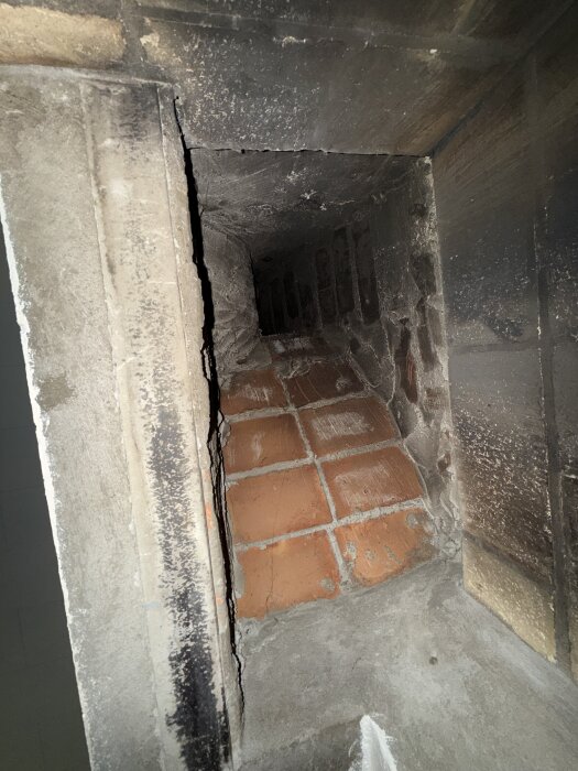 Insidan av en braskamin med tegel och murbruk syns, vilket kan indikera materialets sammansättning och potentiell eternitnärvaro.