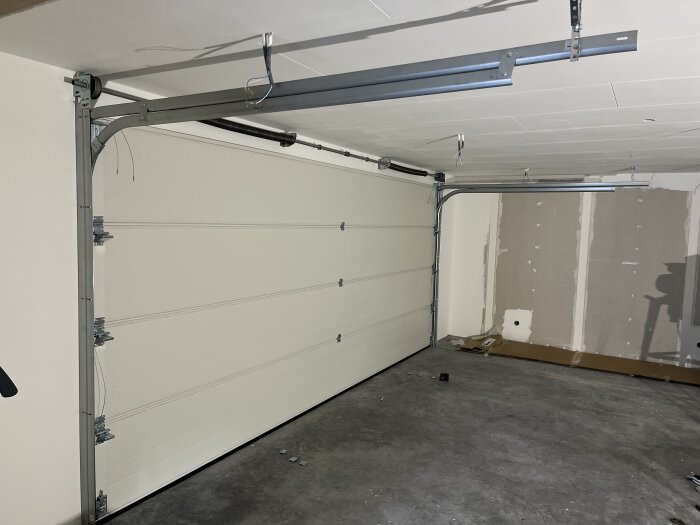 Inåtgående 4-bladig Prido-port monterad i garage med takskjutdörrar och väggar under renovering.