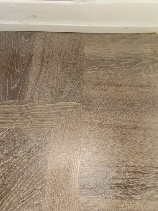 Närbild av nyslipat trägolv med mönster, synliga sliprosor och små märken.