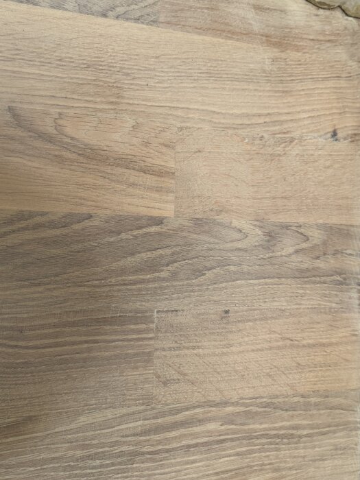 Närbild på nylagt parkettgolv med synliga slipmärken och ojämnheter i ytan.