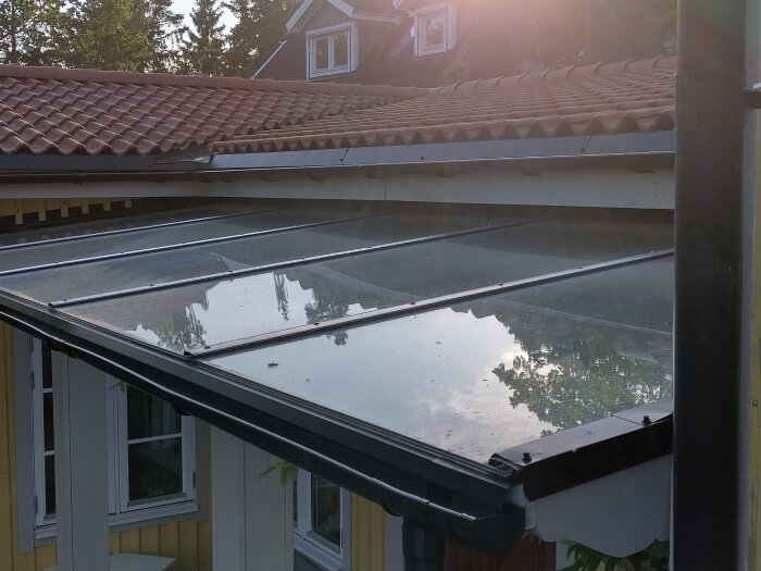 Glastak med hängränna på en villa, reflekterande himmel och träd. Installationen utförd av Allservicegruppen i Stockholm.