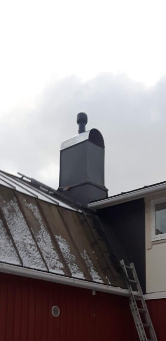 Vilpe takfläkt på ett snötäckt tak med stege lutad mot byggnaden.